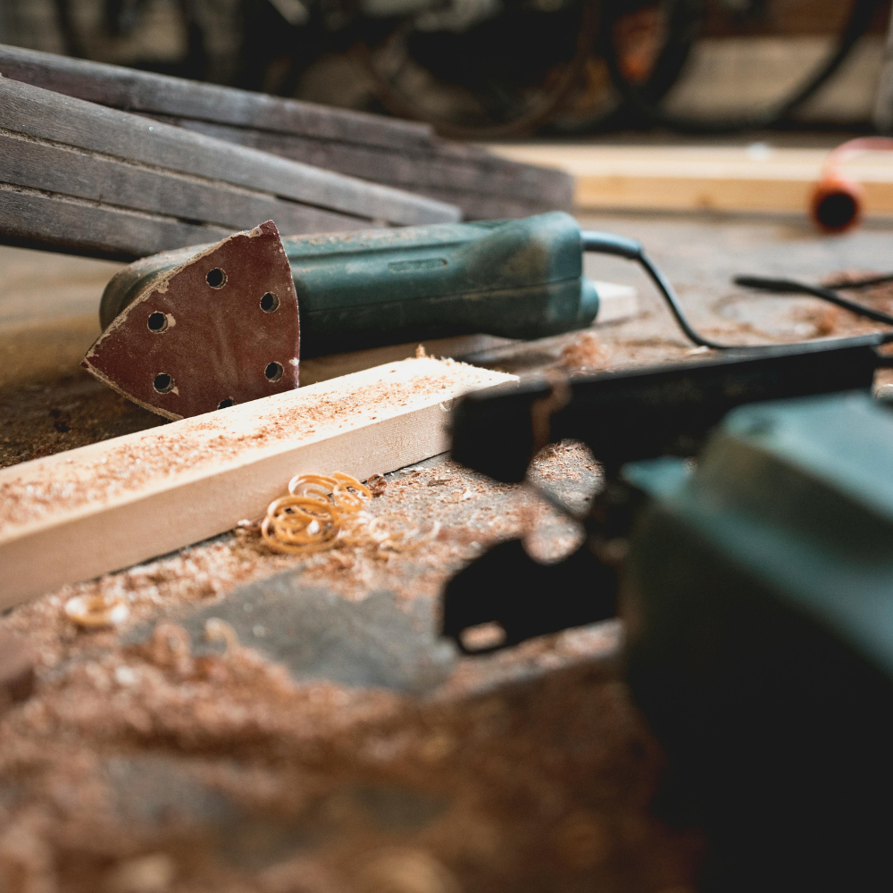 Electric sander next to a block of wood with shavings